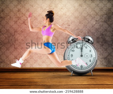 Fit brunette running and jumping against room with wallpaper