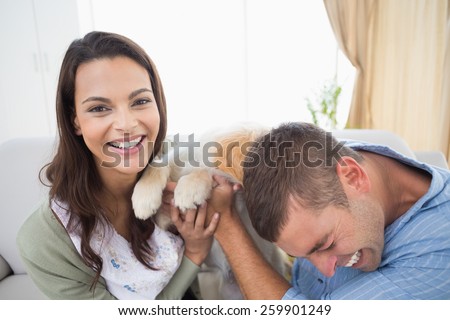 Playful couple with puppy at home
