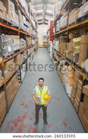 Worker holding hard hat and clipboard in warehouse