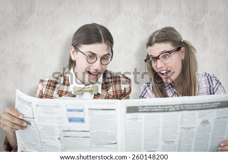Geeky hipsters reading the newspaper against white background