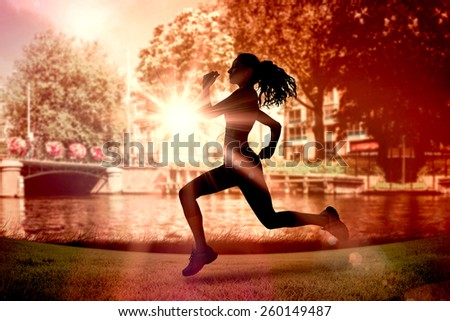 Full length of healthy woman jogging against sun shining over park