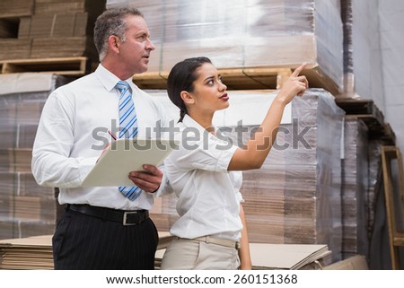 Warehouse manager and her boss checking inventory in a large warehouse