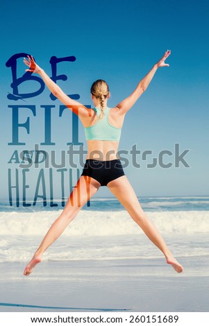 Fit woman jumping on the beach with arms out against be fit and healthy