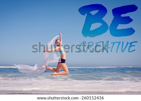 Fit woman jumping gracefully on the beach with scarf against be creative