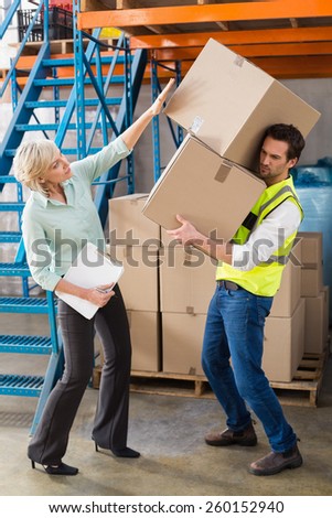 Worker balancing heavy cardboard boxes in a large warehouse