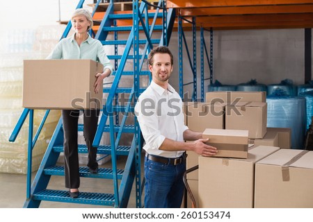 Warehouse managers loading a trolley in a large warehouse