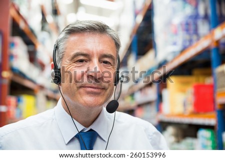 Warehouse manager giving orders on headset in a large warehouse