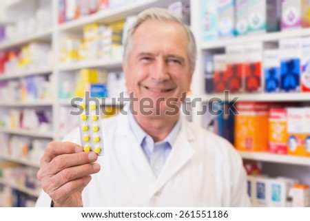 Senior pharmacist holding blister packs at hospital pharmacy
