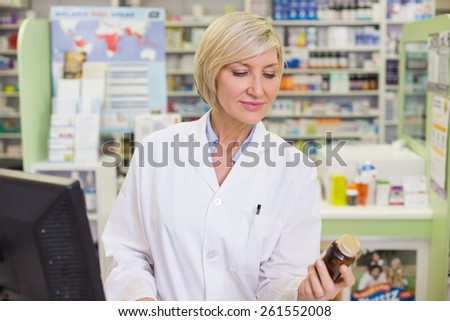 Pharmacist looking at medicine bottle at pharmacy