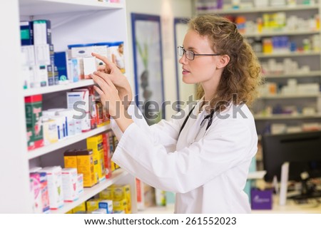Smiling pharmacist taking jar from shelf in the pharmacy