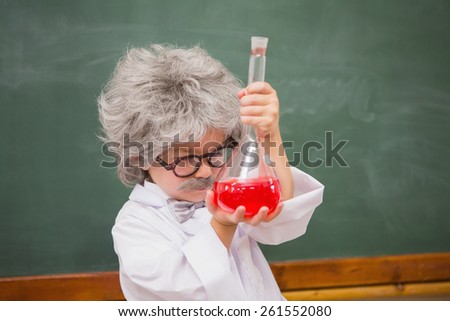 Dressed up pupil looking at red liquid at elementary school