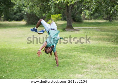 Hipster doing back flip in the park on a sunny day