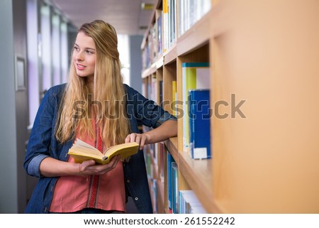 Pretty student reading in the library at the university