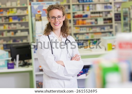 Phamacist in lab coat with stethoscope and arms crossed in the pharmacy