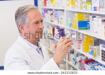 Senior pharmacist taking medicine from shelf at the hospital pharmacy