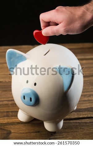 Hand putting heart in piggy bank shot in studio