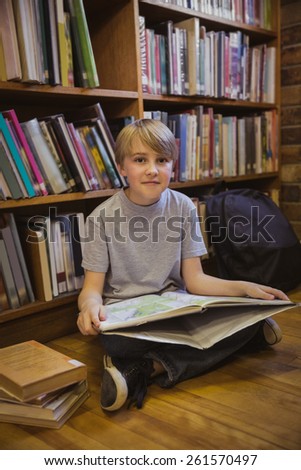 Little boy reading on library floor at the elementary school
