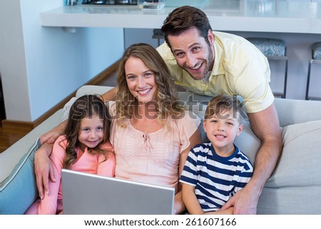 Happy family on the couch together using laptop at home in the living room
