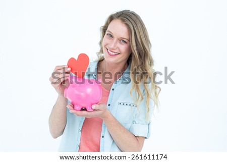 Smiling woman holding piggy bank and red heart on white background