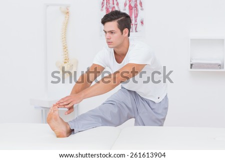 Patient stretching his leg on bed in medical office