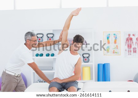 Doctor stretching a young man arm in medical office