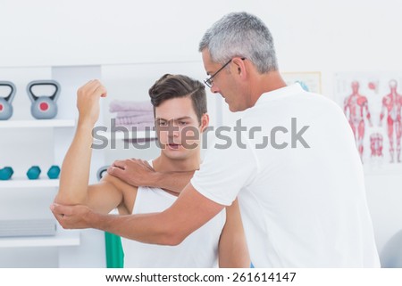 Doctor stretching a young man arm in medical office