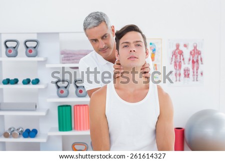 Doctor massaging a young man neck in medical office