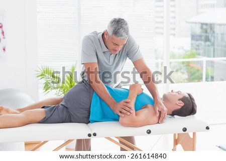Doctor stretching a young man back in medical office