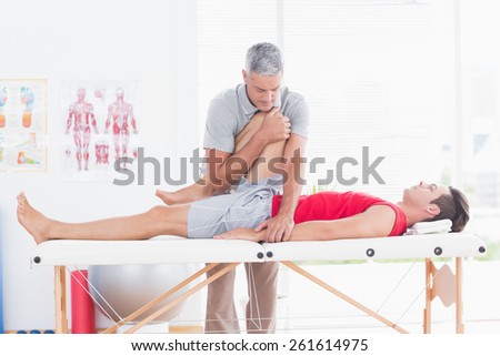Physiotherapist doing leg stretching to his patient in medical office