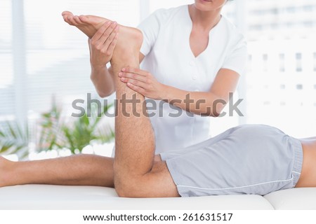 Physiotherapist doing leg massage to her patient in medical office