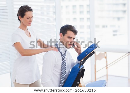 Businessman having back massage while talking on the phone in medical office