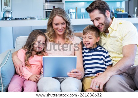 Happy family on the couch together using tablet at home in the living room