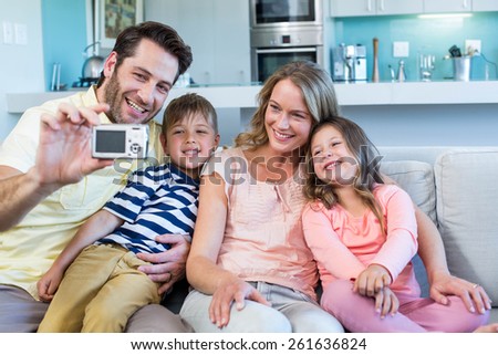Happy family taking selfie on couch at home in the living room