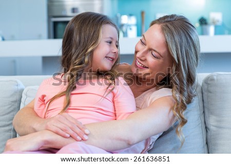 Mother and daughter hugging on couch at home in the living room