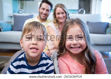Happy family smiling at camera at home in the living room