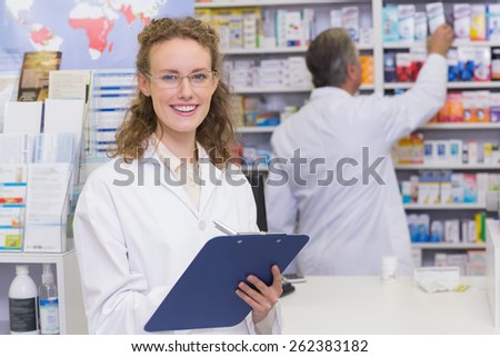 Pharmacist writing on clipboard at the hospital pharmacy