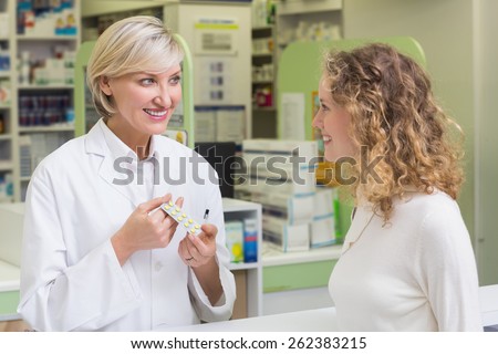 Pharmacist showing blister packs to costumer at pharmacy