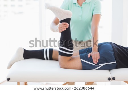 Doctor examining man leg in medical office
