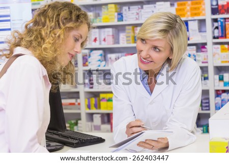 Pharmacist showing prescription to a customer at pharmacy