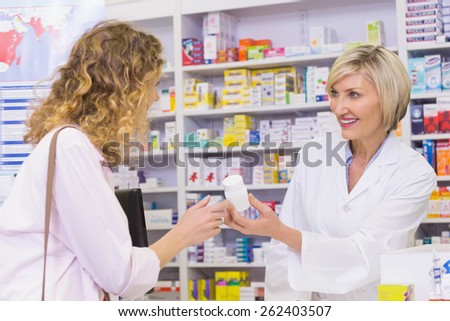 Smiling pharmacist holding a medicine jar at pharmacy