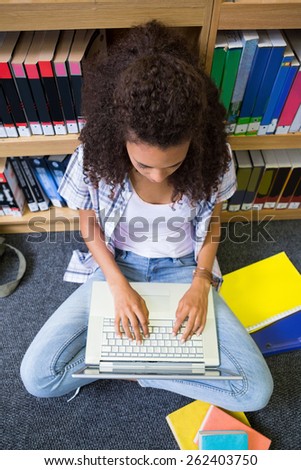 Student sitting on floor in library using laptop at the university