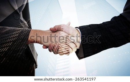 Close up of two businesspeople shaking their hands against low angle view of skyscrapers