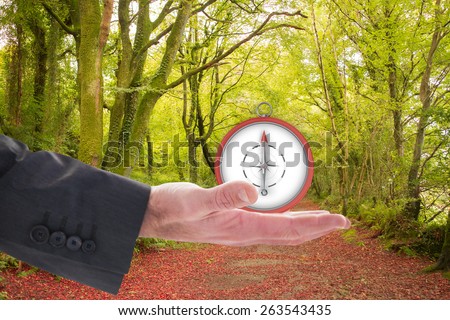 Businessman holding hand out in presentation against peaceful autumn scene in forest
