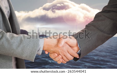 Two people having a handshake in an office against calm sea with lighthouse