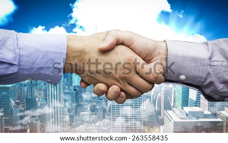 Hand shake in front of wires against city skyline