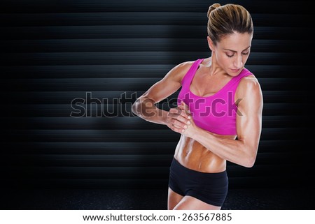 Female bodybuilder flexing with hands together against black background