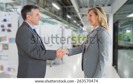 Pleased businessman shaking the hand of content businesswoman against college hallway