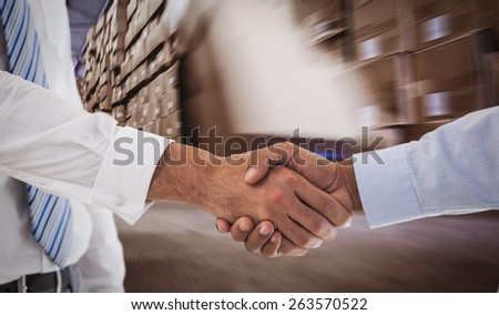 Close-up shot of a handshake in office against worker with fork pallet truck stacker in warehouse