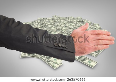 Businessman reaching hand out against pile of dollars