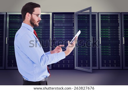 Businessman scrolling on his digital tablet against server towers